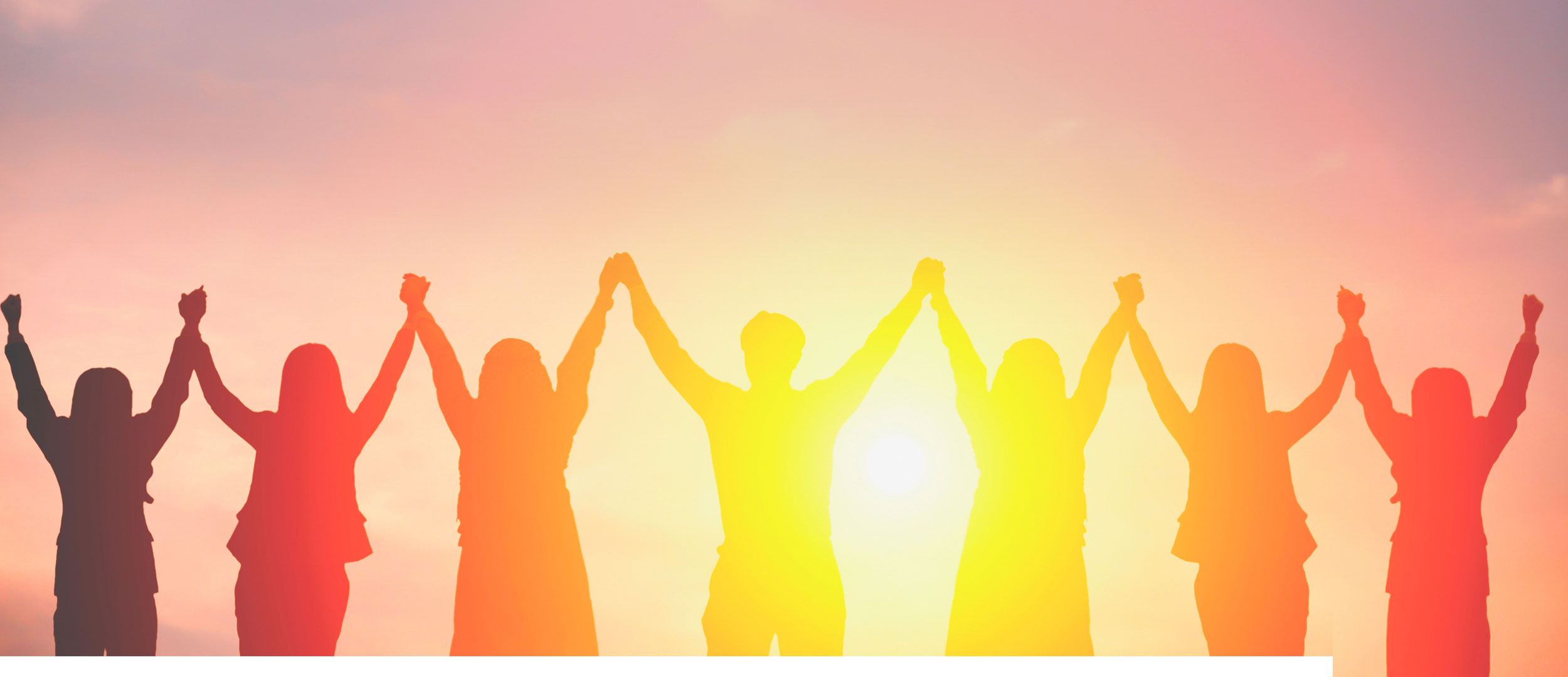 Children holding hands together in the air with the sun shining behind them